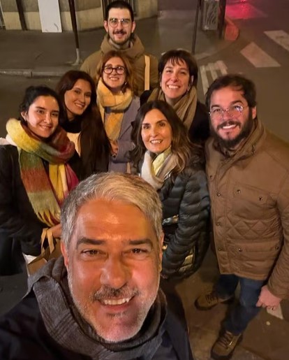 F&aacute;tima Bernardes e William Bonner posam sorridentes ao lado de seus c&ocirc;njuges e filhos durante viagem.

